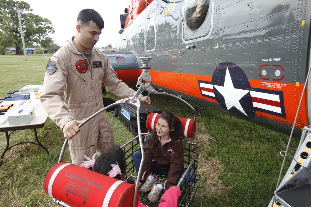 Cpl. Paul Petrella, a search and rescue crew chief with Marine Transport Squadron 1, shows two young visitors a rescue basket attached to the unit’s HH-46 helicopter at the emergency preparedness fair at Marine Corps Air Station Cherry Point, N.C., May 3, 2013. The station hosted the fair to educate Cherry Point residents how to survive severe weather as well as other life threatening situations, like house fires.