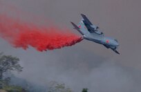 U.S. Air Force C-130E from the 146th Airlift Wing, Channel Island Air National Guard, dispenses fire retardent on the Simi fire in southern California. 