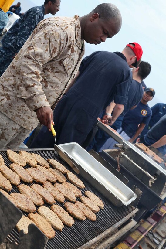 William W. Harrell, training chief, Combat Logistics Battalion 15, 15th Marine Expeditionary Unit, grills burgers during a steel beach picnic aboard USS Peleliu, May 8. During the last leg of the deployment, families and friends came aboard the ship to experience life on the Peleliu and to learn what their Marine or sailor has accomplished during the past seven months. The 15th MEU is comprised of approximately 2,400 Marines and sailors and is deployed as part of the Peleliu Amphibious Ready Group. Together, they provide a forward-deployed, flexible sea-based Marine Air Ground Task Force capable of conducting a wide variety of operations ranging from humanitarian aid to combat. Harrell, 41, is from the District of Columbia (U.S. Marine Corps photo by Cpl. Timothy Childers / Released)