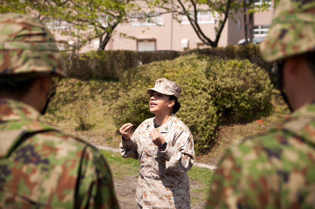 Staff Sgt. Cynthia E. Vasquez explains drill movements to members of the Japan Self Defense Force April 26 at Camp Itazuma, Gotenba, Shizuoka prefecture, Japan, as part of their basic enlisted English course curriculum. Vasquez volunteered to judge the drill competition for the JSDF 3rd Sergeants Training Unit’s basic enlisted English course. “The experience was well worth the time because it allowed me to see something that not a lot of people can say they’ve seen, and my participation directly reflects the Corps’ ongoing commitment to fostering good relations with our allies,” said Vasquez, a former drill instructor who now serves as the postal chief for Headquarters Company, Camp Fuji. (U.S. Marine Corps photo by Cpl. Adam B. Miller/Released)
