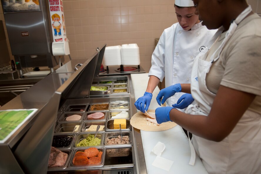 A culinary student from a local high school learns how to prepare a tortilla wrap at Holloman Air Force Base, N.M., May 8. The students visited the Shifting Sands Dining Facility to learn how the military plans, prepares and serves thousands of meals a day to its personnel. The students were divided into small groups and received hands-on experience in napkin folding, garnishing, serving and cooking. (U.S. Air Force photo by Airman 1st Class Colin Cates/Released) 