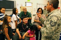 Tech. Sgt. Sergio Avalos, Jr.,15th Operations Support Squadron survival evasion resistance and escape specialist, right, holds up a miniature Leatherman as he explains to Damon Hall-Kaneakua, center in wheelchair, and his family, the items contained in an aircrew member’s survival kit, at Joint Base Pearl Harbor-Hickam, Hawaii, May 3, 2013. Hall-Kaneakua was a guest of the 15th Wing as part of the Pilot for a Day program that gives children with serious or chronic conditions a special day and a break from whatever challenges they may face. (U.S. Air Force photo/Tech. Sgt. Phyllis E. Keith)