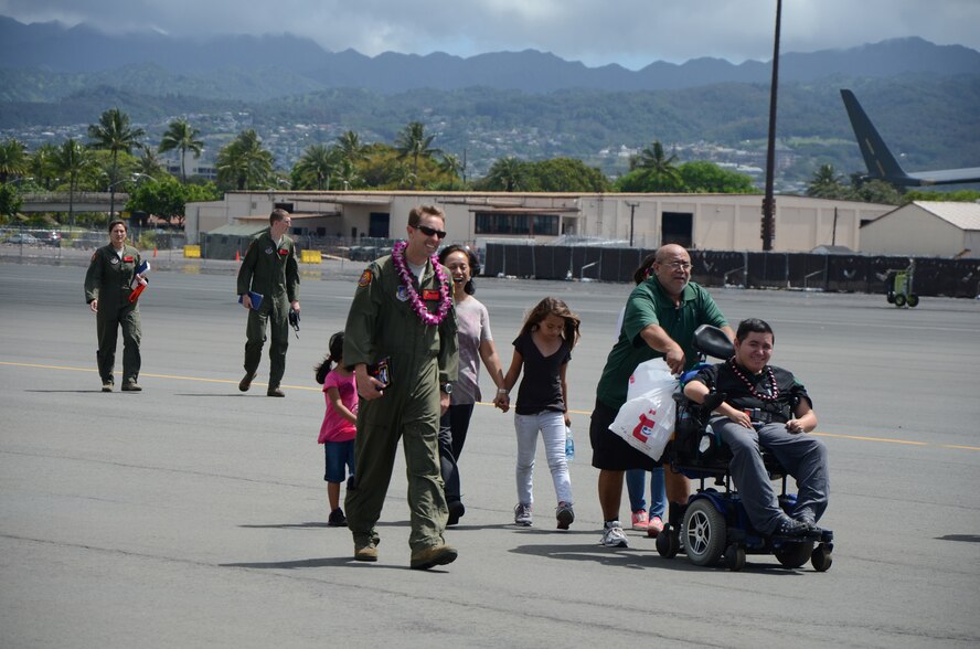 Capt. Rush H. Taylor, center, 15th Operations Support Squadron, coordinator of the Pilot for a Day program, escorts Damon Hall-Kaneakua, far right in wheelchair, across the flightline after he and his family tour a KC-135 Stratotanker and a C-17 Globemaster III as guests of the 15th Wing, Joint Base Pearl Harbor-Hickam, Hawaii, May 3, 2013. Hall-Kaneakua has Duchenne muscular dystrophy and was recommended for the Pilot for a Day program by Kapiolani Hospital who partnered with the 15th Wing on this community service project. (U.S. Air Force photo/Tech. Sgt. Phyllis E. Keith)