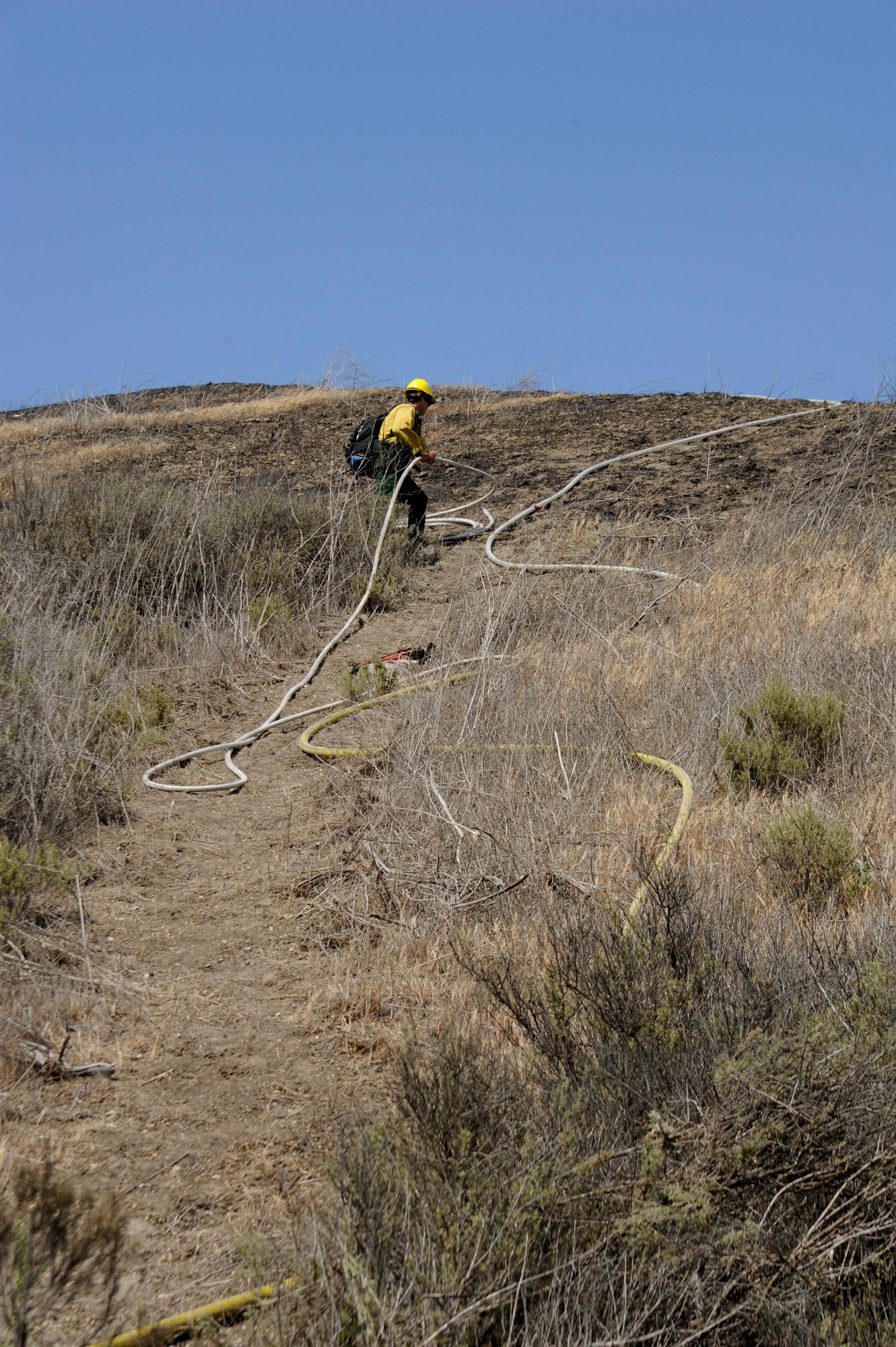 VANDENBERG AIR FORCE BASE, Calif. – A Vandenberg Fire Department firefighter coils a hose in order to douse an area of land with water while containing a brush fire on Highway 1 here Wednesday, May 9, 2013. Vandenberg firefighters were the first responders to the 10 acre fire and, with the help of the Santa Barbara County Fire Department and the U.S. Forest Service, contained the fire within two hours. (U.S. Air Force photo/Senior Airman Lael Huss)