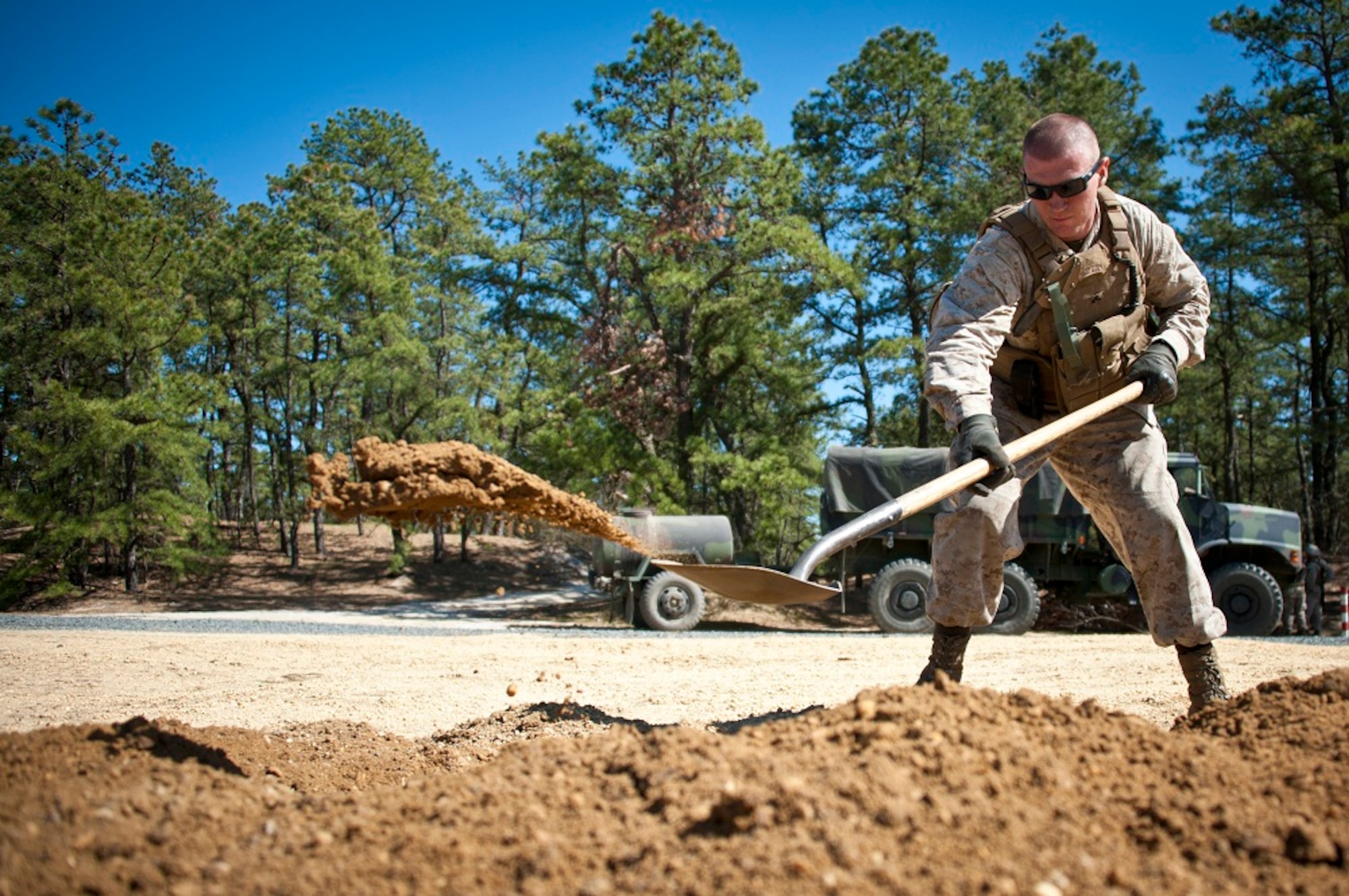 Cpl. James Heitzer, Golf Battery 3rd Battalion, 14th Marine Regiment field artillery cannoneer, pitches dirt as he builds a cover hole during artillery training May 4, 2013, on the Joint Base McGuire-Dix-Lakehurst ranges. The unit simulated a real-world combat environment by digging cover holes to take cover during enemy fire. Heitzer is a Mays Landing, N.J., native. (U.S. Air Force photo by Staff Sgt. David Carbajal/Released)