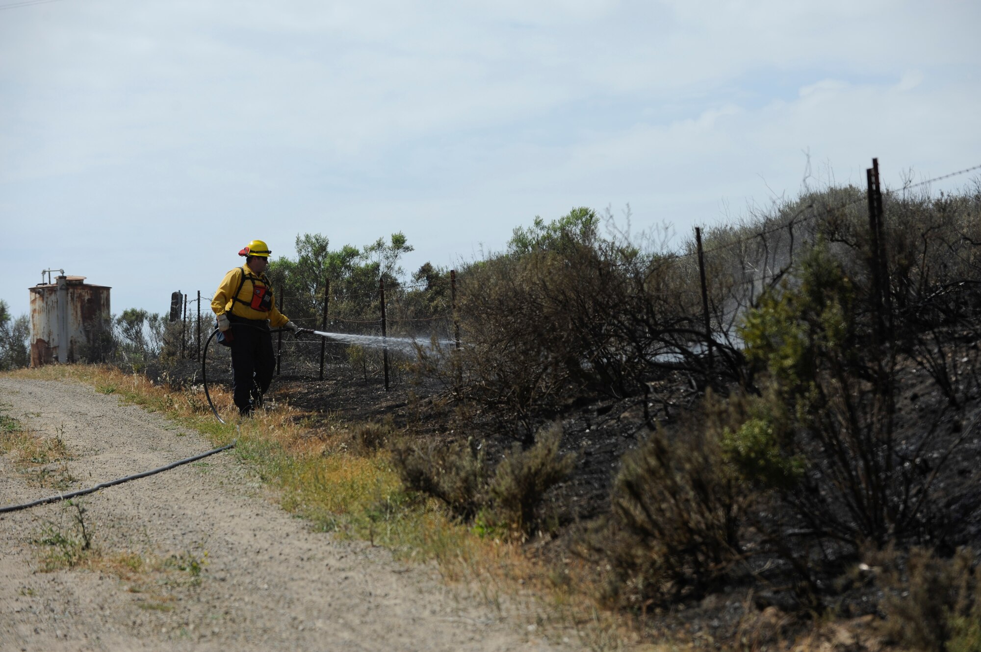 VANDENBERG AIR FORCE BASE, Calif. – A Santa Barbara County firefighter sprays smoldering ashes with water during a cooperative effort to control a blaze on Highway 1 here Wednesday, May 9, 2013. The Vandenberg Fire Department, Santa Barbara County Fire Department and the U.S. Forest Service joined forces to control the 10 acre fire within a two hour time frame. (U.S. Air Force photo/Senior Airman Lael Huss)