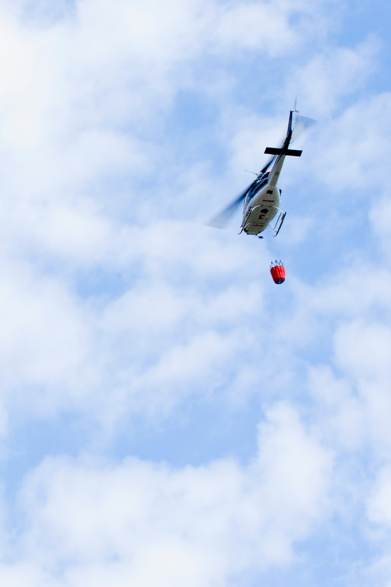 VANDENBERG AIR FORCE BASE, Calif. –A helicopter transports a bucket of flame retardant material to drop on a fire beside Highway 1 here Wednesday, May 9, 2013. The seven to 10-acre fire located a half-mile north of San Antonio Road West was contained within two hours. (U.S. Air Force photo/Airman Yvonne Morales) 