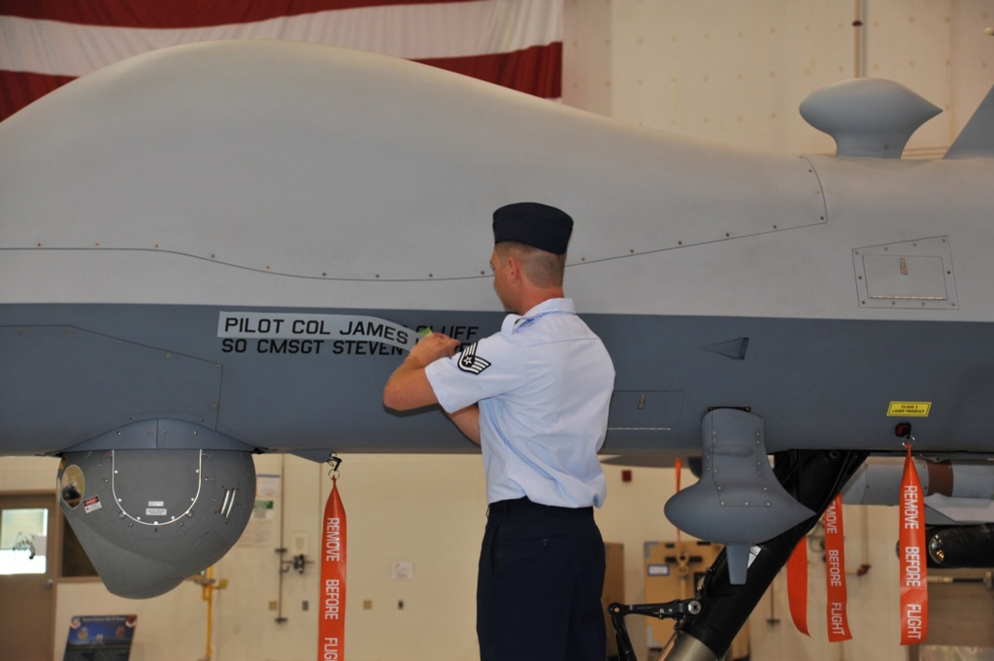 LAS VEGAS, Nev. -- The name of former 432nd Wing and 432nd Air Expeditionary Wing Commander, Col. James Hecker, is removed from an MQ-9 Reaper to reveal the name of the new wing commander, Col. Jim Cluff, during a symbolic ceremony May 3, 2013. (U.S. Air Force photo by Senior Airman A.K./Released)