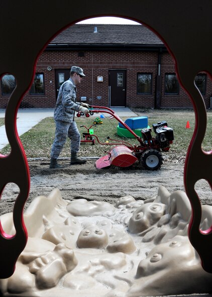 Airman 1st Class Justin Emanuelson, 319th Civil Engineer Squadron heavy equipment operator, maneuvers a tiller around the sandbox at the Child Development Center, May 7, 2013, on Grand Forks Air Force Base, N.D. The 319th CES works on the sand twice a month during the summer, or as needed, to prevent it from hardening and potentially harming children. (U.S. Air Force photo/Airman 1st Class Ashley Nicole Taylor)