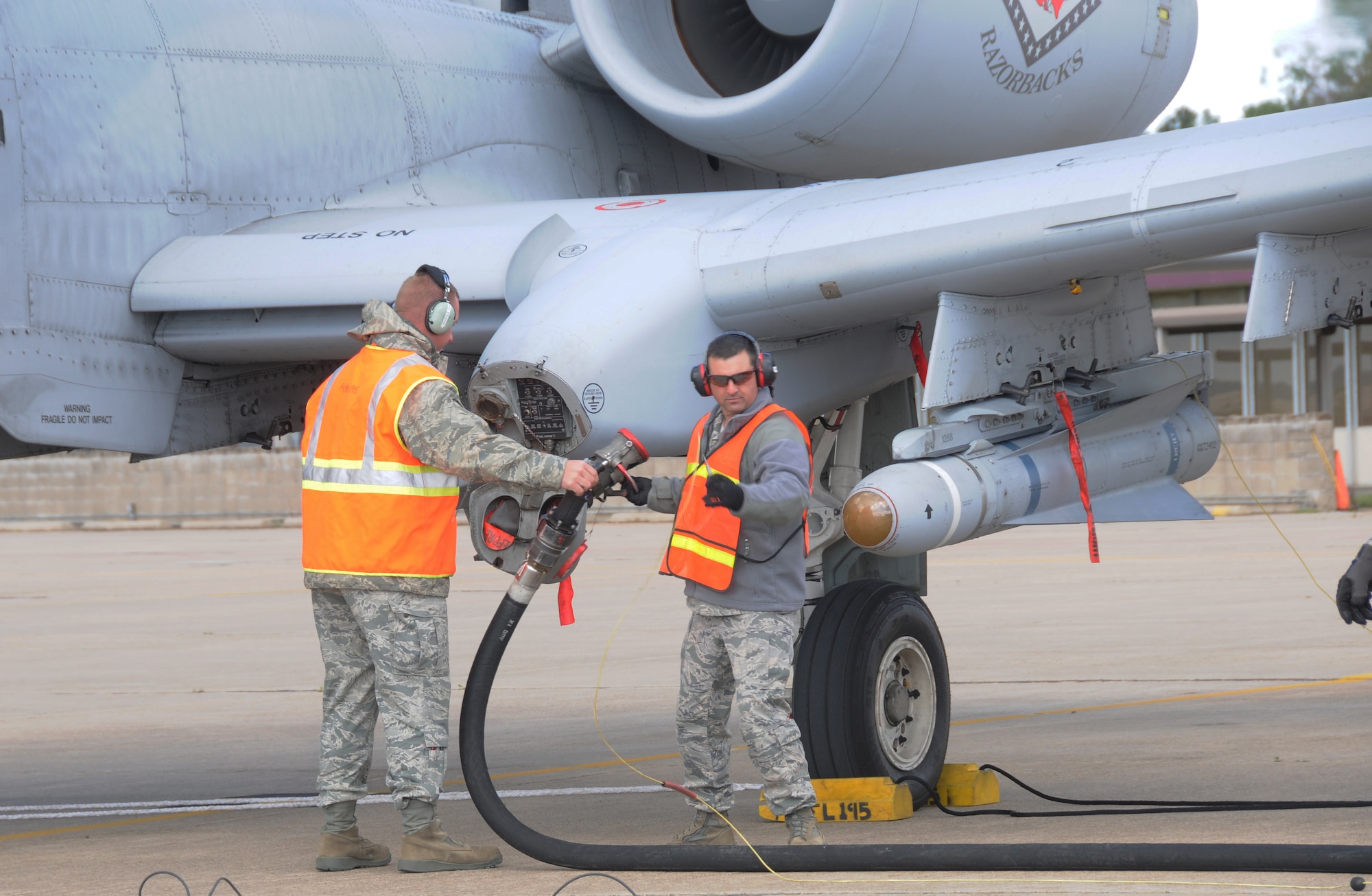 Staff Sgt. Nick Warrick of the 188th Fighter Wing, Arkansas Air National Guard, passes a fuel hose to Technical Sgt. Briane McCaslin after a hot-pit refueling of an A-10C Thunderbolt II at Ebbing Air National Guard Base, Fort Smith, Ark., April 24, 2013. (U.S. Air National Guard photo by Senior Airman John Hillier/188th Fighter Wing Public Affairs)