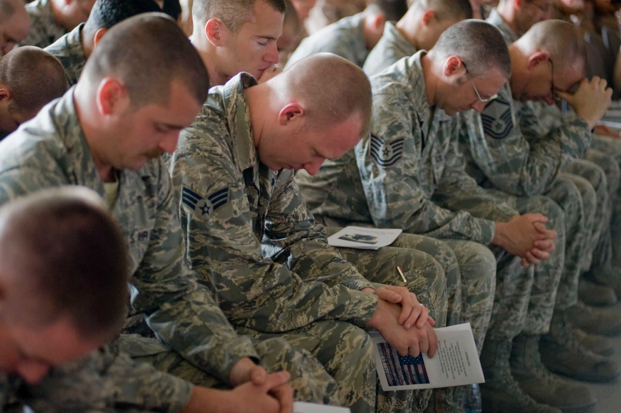 Airmen bow their heads in prayer during a memorial service May 9, 2013, at Transit Center at Manas, Kyrgyzstan. Fellow friends of fallen crew members Capt. Mark "Tyler" Voss, Capt. Victoria "Tori" Pinckney, and Tech. Sgt. Herman "Tre" Mackey III spoke during the service, sharing stories with attendees. (U.S. Air Force photo/Staff Sgt. Stephanie Rubi)
