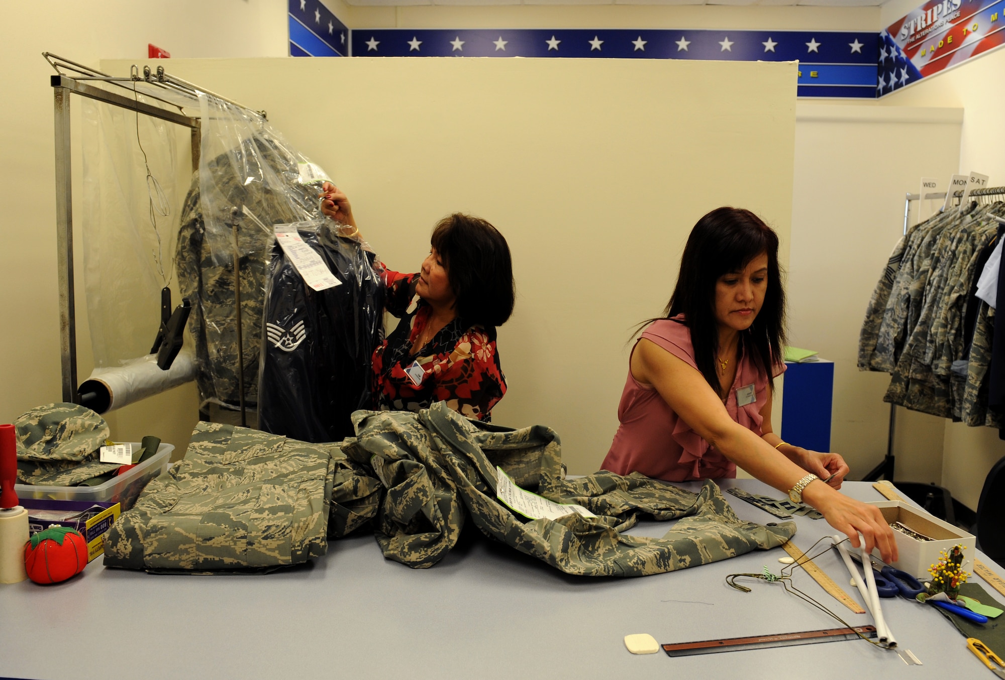 Tam Harper, left, and Jantip Sangpron, Army & Air Force Exchange Service alterations seamstresses, prepare uniforms for alterations on Barksdale Air Force Base, La., May 8, 2013. The AAFES Cleaners and Alterations shops are open Monday to Friday from 8:00 a.m. to 6:00 p.m., Saturday from 9:00 a.m to 4:00 p.m. and are closed every Sunday and on holidays. (U.S. Air Force photo/Airman 1st Class Benjamin Gonsier)
