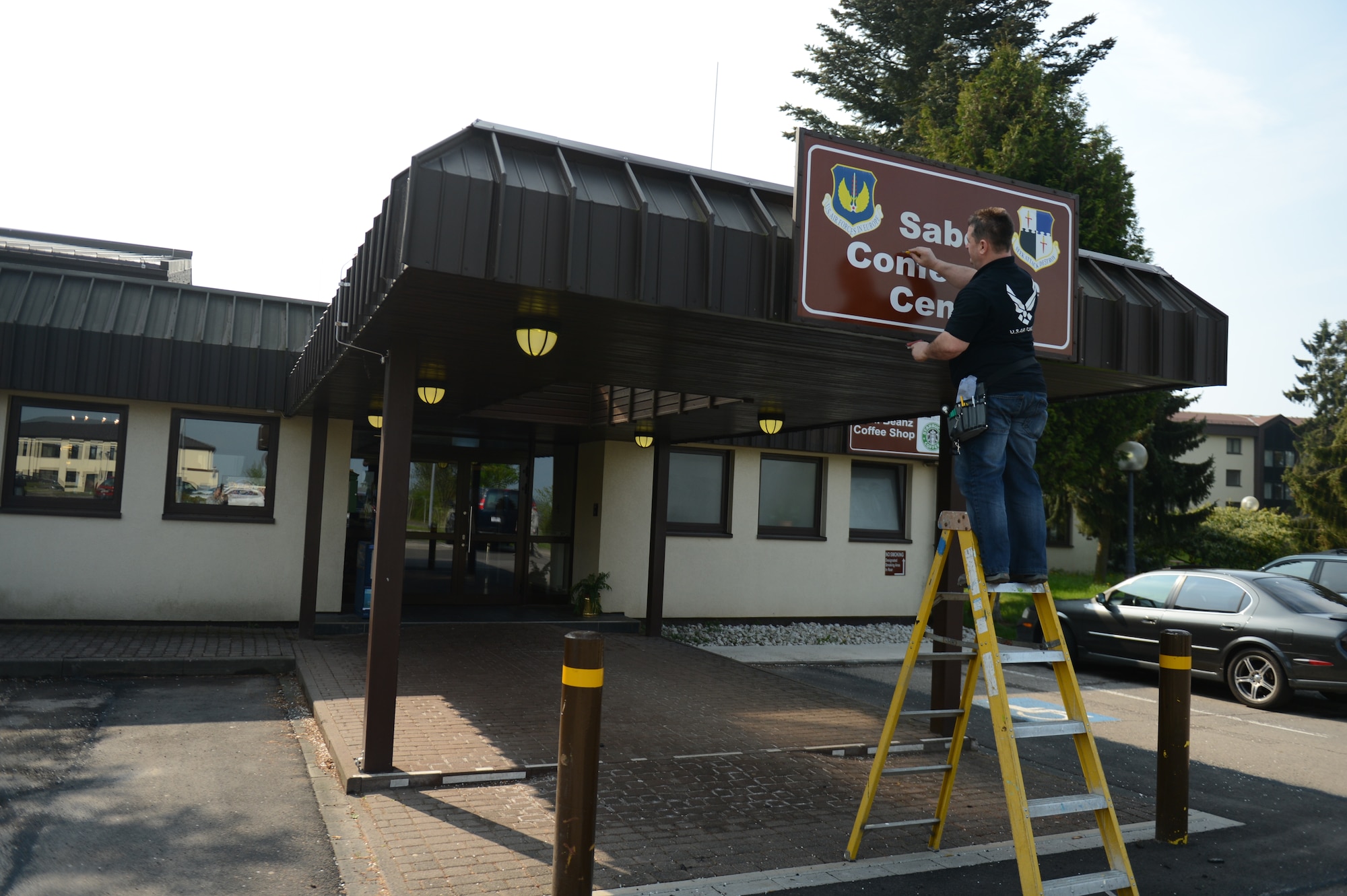 SPANGDAHDLEM AIR BASE, Germany – Erich Kreiner, 52nd Civil Engineer Squadron sign painter, installs the new Saber Conference Center sign May 8, 2013. The Saber Conference Center is a focal point for new members when arriving to Spangdahlem due to it being the location of newcomer briefings. Creating the best look possible for the building is meant to give a positive first impression on all incoming Sabers. (U.S. Air Force photo by Airman 1st Class Gustavo Castillo/Released)