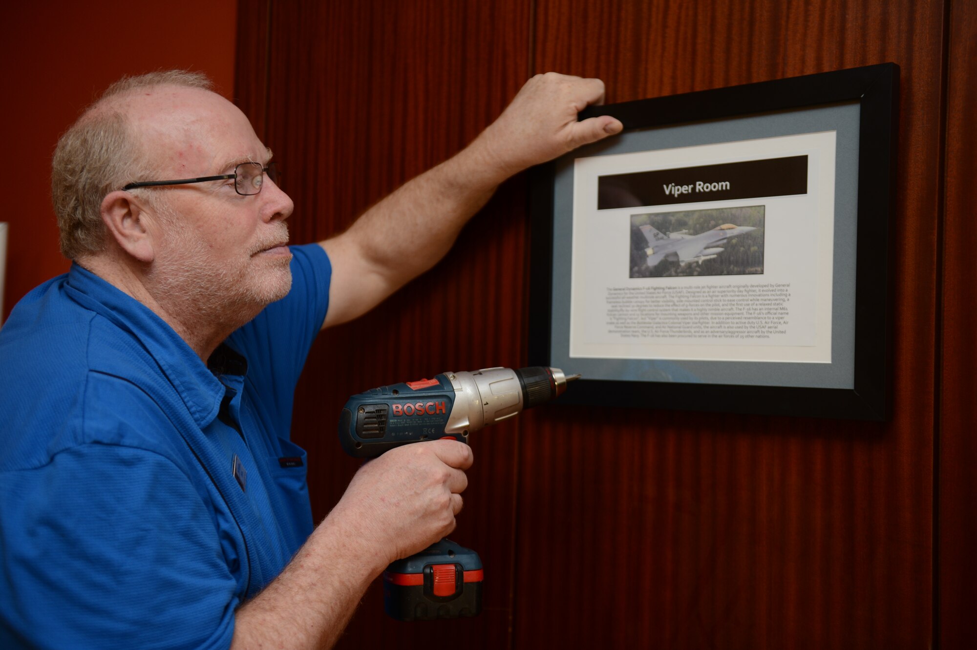 SPANGDAHLEM AIR BASE, Germany – Bob Rosinbum, Eifel Community Center director from Seattle, positions a sign near a doorway at the Saber Conference Center May 8, 2013. The renaming of the conference rooms to titles such as the Viper Room, Warthog room, Phantom Room and Eagles Corner is a tribute Spangdahlem’s heritage.(U.S. Air Force photo by Airman 1st Class Gustavo Castillo/Released)