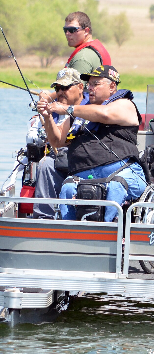 David Aguiler, foreground right, baits his line for another cast, while Daniel Hernandez, left, and a volunteer crew member look on. Photo cropped for emphasis.