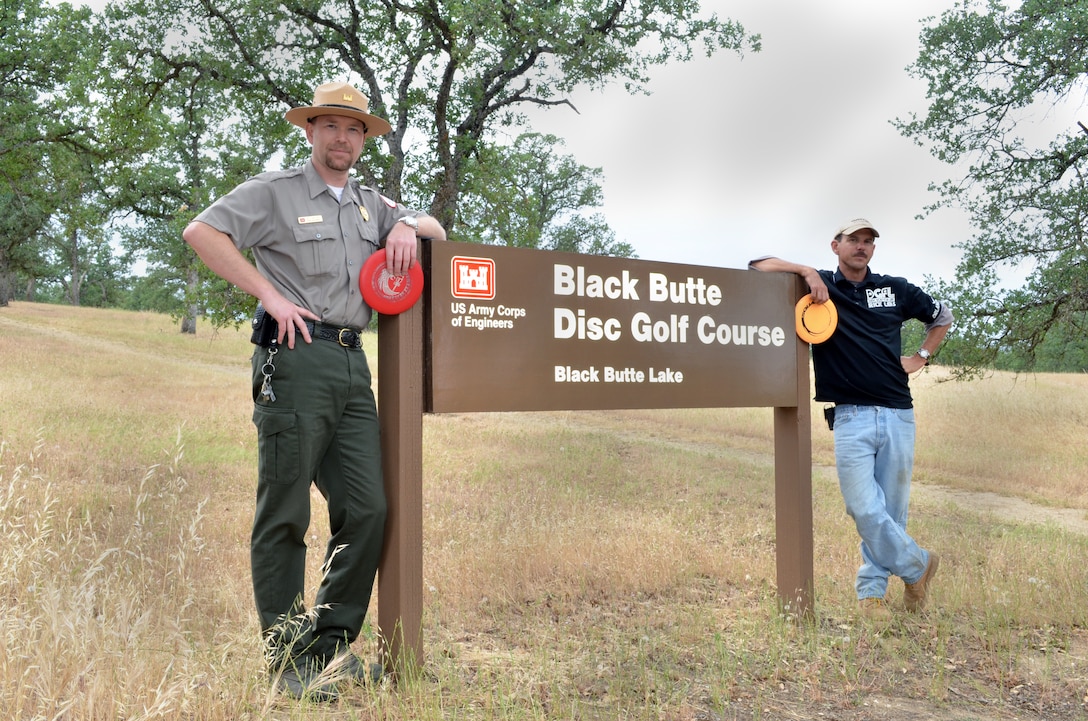 Black Butte Lake Senior Ranger Bill Miller (left) and Rick Leis, president of the Orland ACES Disc Golf Club, pose by the sign for the 18-hole disc golf course at the U.S. Army Corps of Engineers Sacramento District park near Orland, Calif. (U.S. Army Corps of Engineers photo by Robert Kidd/Released)