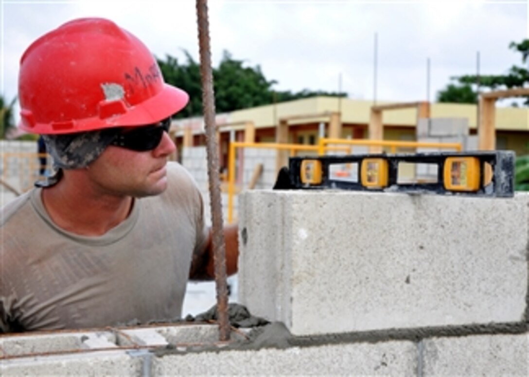 U.S. Air Force Staff Sgt. Matthew Morrison levels a concrete block at the construction site of the Louisiana Government Primary School in Belize on April 30, 2013.   Civil engineers from both the U.S. and Belize are building various structures at schools throughout Belize as part of exercise New Horizons.  The construction will provide valuable training for U.S. and Belizean service members and will support further education for the children of Belize.  Morrison is attached to the 823rd Red Horse Squadron.  