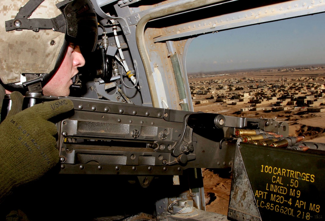 U.S. Marine Corps Lance Cpl. Joe Berry, a CH-46 crew chief with Marine Medium Helicopter Squadron 161, holds a .50-caliber rifle as he looks down on Ramadi, Iraq, during an urgent casualty evacuation mission, Jan. 16, 2006.