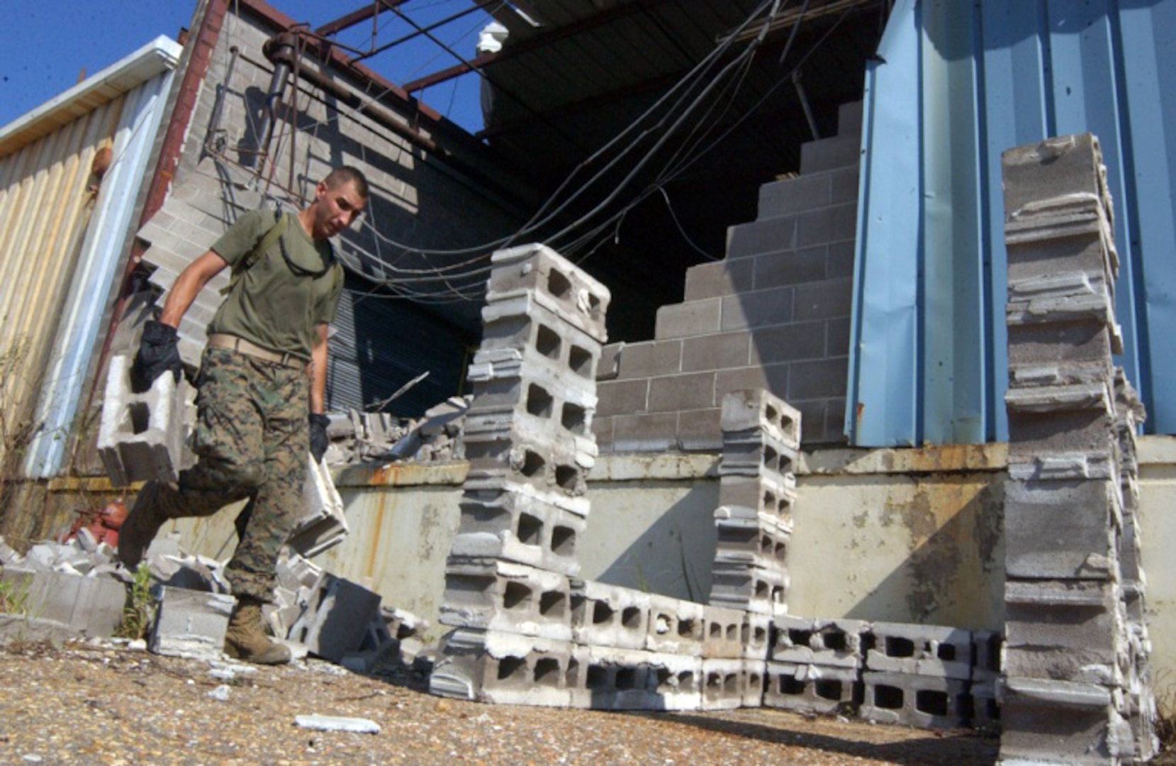 A Marine from the Marine Expeditionary Unit Service Support Group- 11, 11th Marine Expeditionary Unit, Camp Pendleton, Calif., assists the American, English and Spanish Red Cross’ volunteers here to clean and salvage a warehouse left ravaged by Hurricane Katrina, Sept. 8. The Marines also assisted in unloading thousands of pounds of humanitarian aid for the people of Gulfport, Miss. The warehouse will be used as the central processing and distribution point of donated goods to the community. 