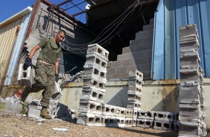 A Marine from the Marine Expeditionary Unit Service Support Group- 11, 11th Marine Expeditionary Unit, Camp Pendleton, Calif., assists the American, English and Spanish Red Cross’ volunteers here to clean and salvage a warehouse left ravaged by Hurricane Katrina, Sept. 8. The Marines also assisted in unloading thousands of pounds of humanitarian aid for the people of Gulfport, Miss. The warehouse will be used as the central processing and distribution point of donated goods to the community. 