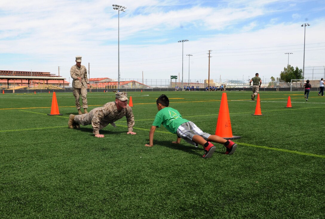 Marine Aircraft Group 13 Marines based at Marine Corps Air Station Yuma, Ariz. volunteered their time for the inaugural Intro to Devil Dogs 101 kid's tour by demonstrating and helping children with the mini-combat fitness course during the mornings events May 8.  The purpose of this event is to increase school-aged childrens' understanding of service in the Marine Corps, build their interest in physical fitness and offer multiple schools a chance to visit the air station prior to the end of the school year.