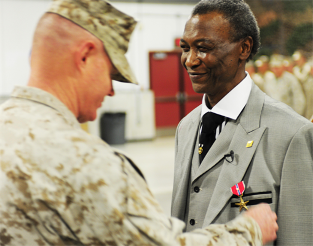 Col. Charles Sides, commanding officer of the 24th Marine Regiment, presents former Pfc. Robert L. Rimpson the Bronze Star Medal with Combat "V" device May 4, during an awards ceremony at the 24th Marine Regiment Drill Hall.