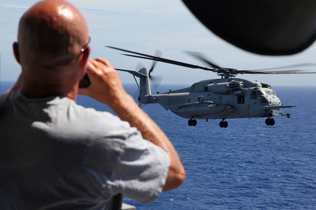 John Coolidge, father of Cpl. Dillon Coolidge, takes a photo of a CH-53E Super Stallion during an air-power display aboard USS Peleliu, May 9. During the last leg of the deployment, guests came aboard the ship to experience life on the Peleliu and to learn what their Marine or sailor has accomplished during the past seven months. The 15th Marine Expeditionary Unit is comprised of approximately 2,400 Marines and sailors and is deployed as part of the Peleliu Amphibious Ready Group. Together, they provide a forward-deployed, flexible sea-based Marine Air Ground Task Force capable of conducting a wide variety of operations ranging from humanitarian aid to combat. (U.S. Marine Corps photo by Cpl. Timothy Childers / Released)