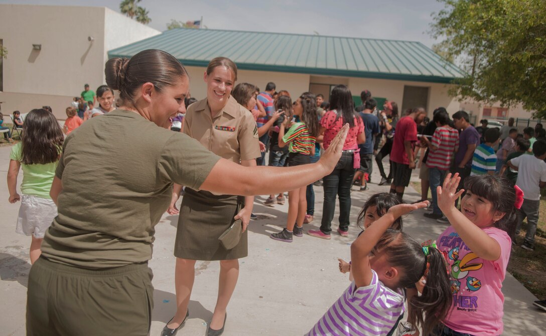 LCpl. Marista Ann Dryden, a Marine Attack Squadron 211 aviation mechanic and a native of Flynt, Mich. (left), and Cpl. Lusetta Elise Lopez, a VMA-211 corrosion control specialist and a native of Spokane, Wash. (right), have a round of high fives with students at George Carver Elementary school after a fun filled day celebration, May 3. The day saw the student body recognize the Marines for their continued and ongoing work with the students and celebrated Cinco De Mayo with performances and traditional music that kept everyone dancing for the duration of the day.