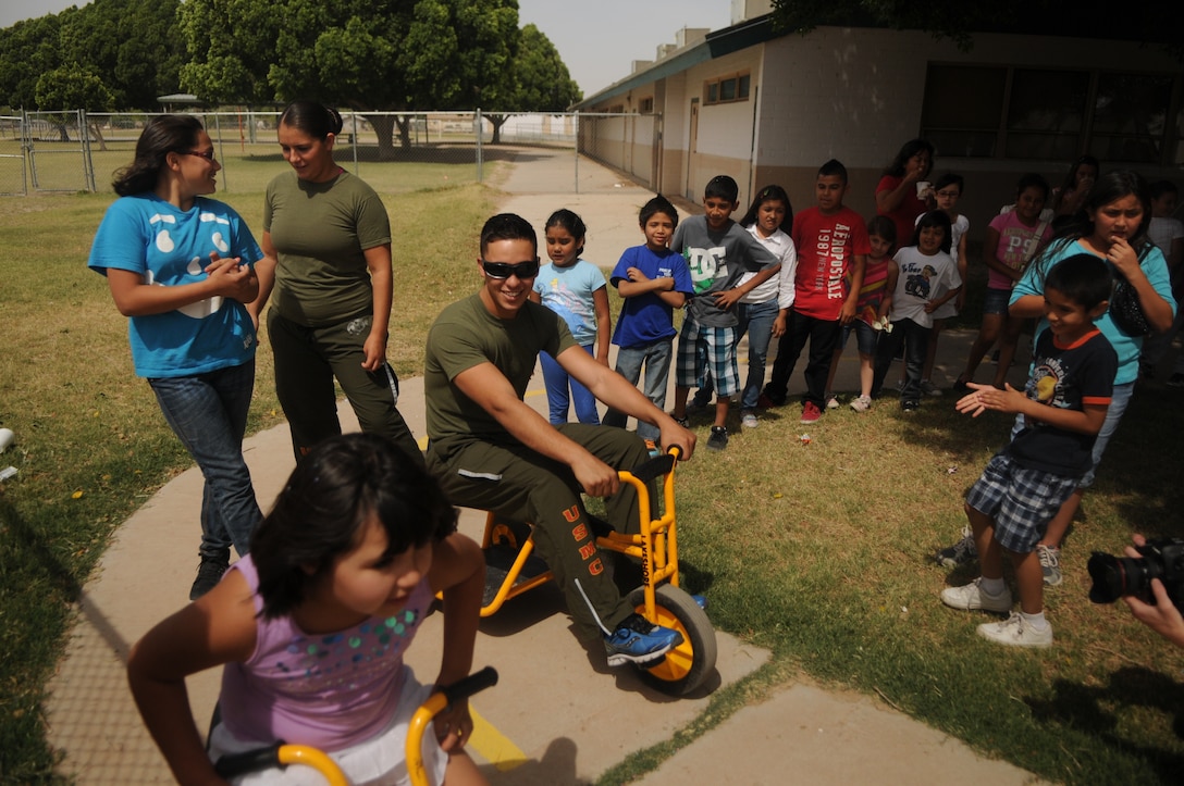 LCpl. Marista Ann Dryden, a Marine Attack Squadron 211 aviation mechanic and a native of Flynt, Mich. (left), and LCpl. Gorge Flores Jr., a VMA-211 egress mechanic and a native of Hamilton, Ohio (right), took part in tricycle races with kids at their squadron’s adopted George Carver Elementary school, May 3. The Wake Island Avengers have been building a close relationship with the kids at the schoolhouse in an effort to foster greater relations with the youngest members of the greater Yuma community. 
