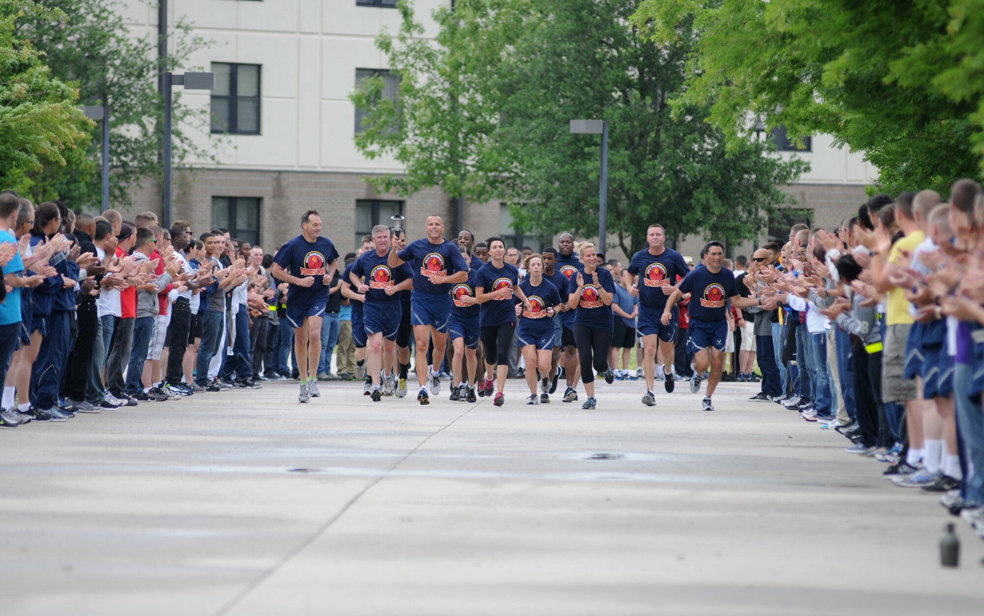 Brig. Gen. Brad Spacy (holding torch), 81st Training Wing commander, and other base leadership lead the Special Olympics Mississippi Summer Games torch through a parade of Airmen as they made their way to light the caldron May 10, 2013, Keesler Air Force Base, Miss.  This is the 27th year Keesler has hosted the state Special Olympics.  (U.S. Air Force photo by Kemberly Groue)