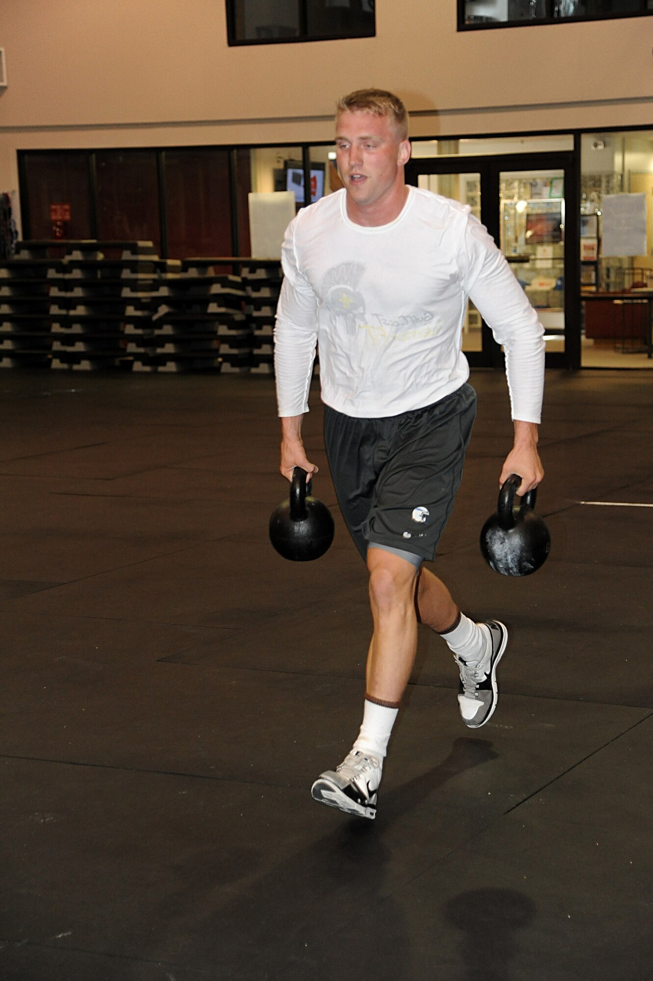 Second Lt. Ross Fleming, 333rd Training Squadron, carries a kettle bell 40-yards while doing a “farmer’s walk” during the warfighter fitness challenge May 9, 2013, at the Dragon Fitness Center, Keesler Air Force Base, Miss.  The timed challenge also consisted of completing activities such as pullups, pushup and situps.  The event was part of Keesler’s support for national sports and fitness month.  (U.S. Air Force photo by Kemberly Groue)