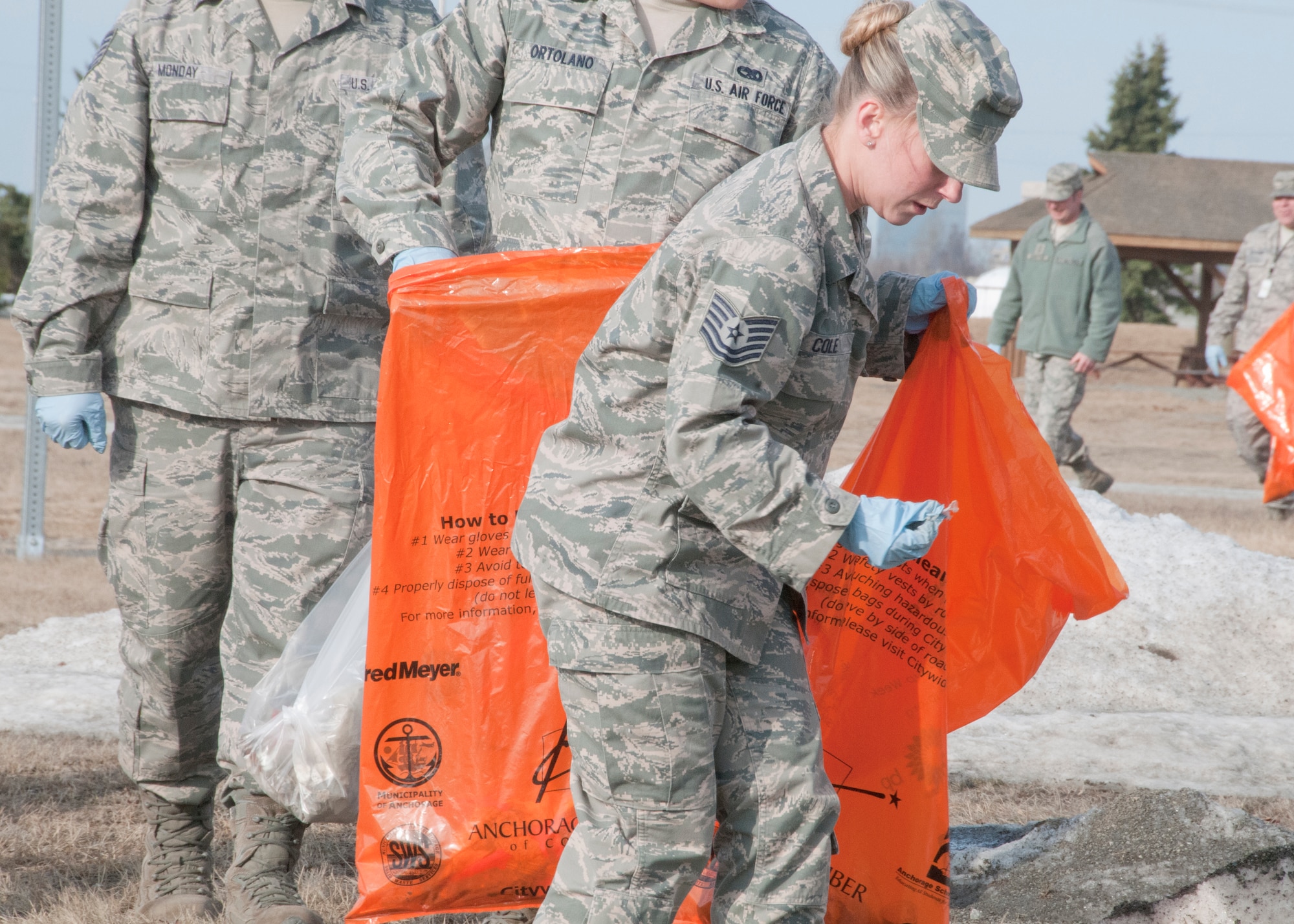 JOINT BASE ELMENDORF-RICHARDSON, Alaska -- Tech. Sgt. Rebecca Cole, a maintenance support technician from the 176 Logistics Readiness Squadron, picks up debris forthe base's Spring Cleanup on May 6. Military members across the base cleaned around their work buildings as the melting snow revealed litter.  National Guard photo by Staff Sgt. N. Alicia Goldberger.