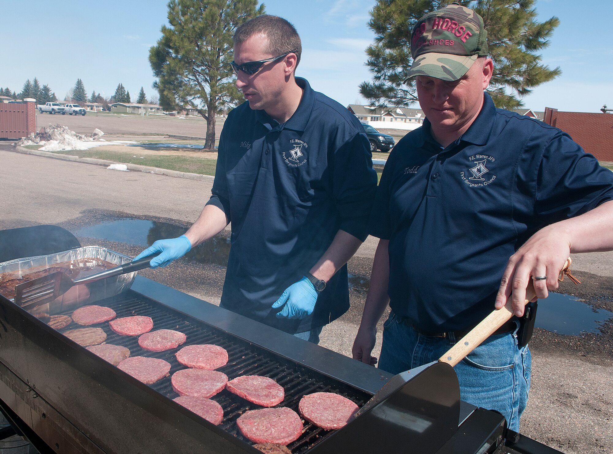 Senior Master Sgt. Mike Green, 90th Comptroller Squadron, and Senior Master Sgt. Todd Meaney, 90th Medical Group first sergeant, grill burgers behind the base clinic May 4, as part of Retiree Appreciation Day. (U.S. Air Force photo by R.J. Oriez)