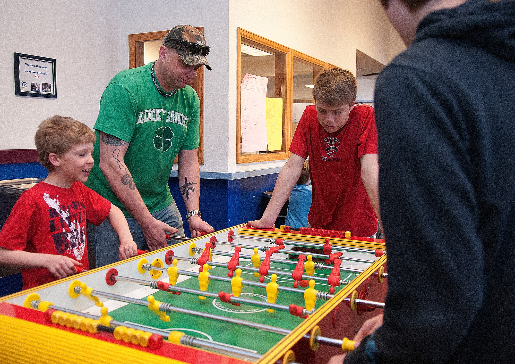 Carter Hill, 7, and his father, Master Sgt. Brian Hill, 90th Missile Wing Command Post, team up in a game of foosball against his brother and a family friend at the F. E. Warren Air Force Base Youth Center April 26 as another brother, Chase, 14, looks on. The Hills were taking part in the youth center’s Month of the Military Child festivities. (U.S. Air Force photo by R.J. Oriez) 