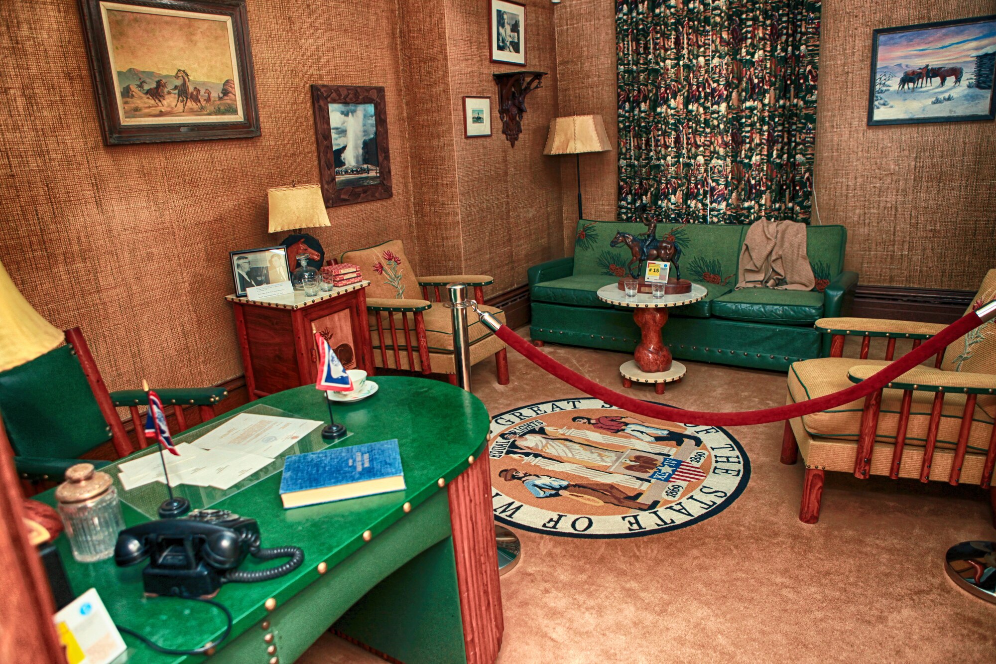 The home office of the Governor of the great state of Wyoming, complete with a landline phone and carpet adorning the walls, an emerald green and mahogany desk, some chairs, a green couch, paintings and a carpet depicting the seal of the state of Wyoming. (U.S. Air Force photo by Matt Bilden)