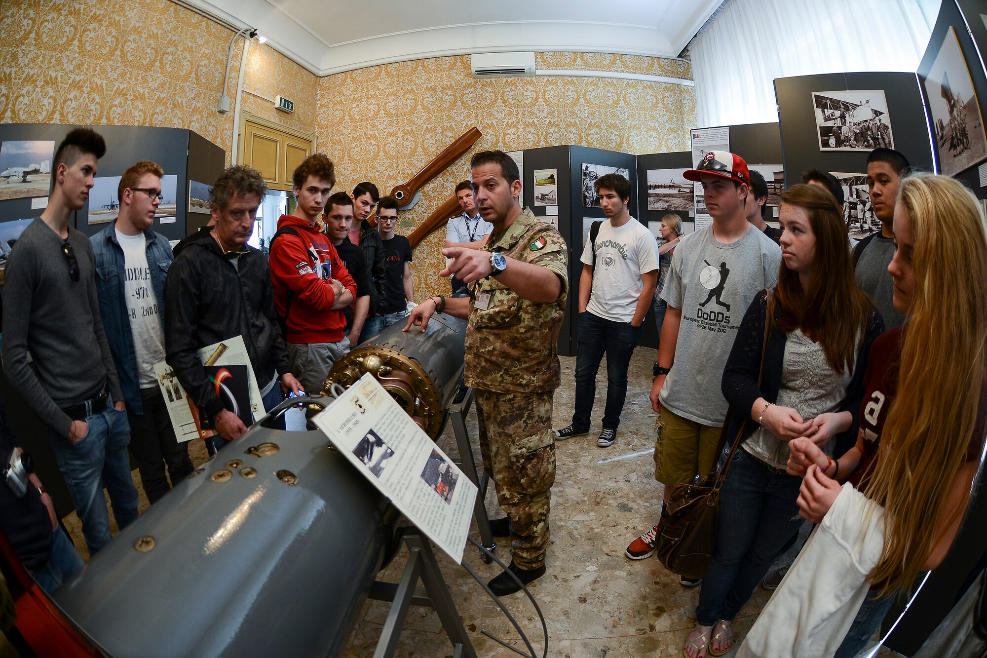 Italian air force Sergente Maggiore Lorenzo Semeraro, speaks to Italian and American students during a base tour May 9 at Aviano Air Base, Italy. Nearly 40 teachers and students from the base’s middle and high school and Italian students from the Leonardo da Vinci Technical Institute in Nanto gathered the tour, which began with a history of the Pagliano e Gori airport and the importance of the mission and the relationship between Italy and the U.S. (U.S. Air Force photo/Staff Sgt. Katherine Tereyama)