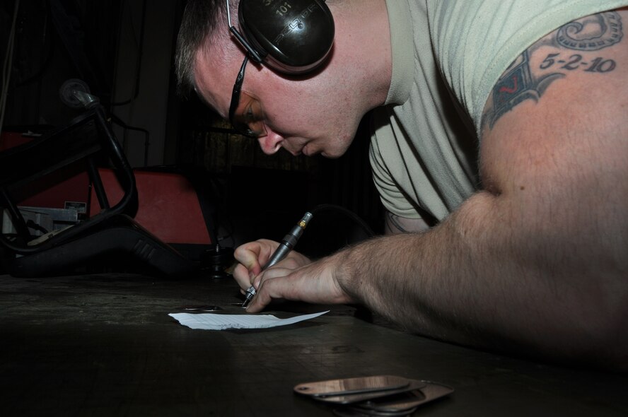 U.S. Air Force Staff Sgt. Michael Durham, 380th Expeditionary Maintenance Squadron Aerospace Ground Equipment production support NCO, uses a pneumatic etcher to engrave tags with identification codes May 8, 2013, here. The tags will be attached to equipment checked out from bench stock and used to ensure accountability by assigning the specific tool code to the Airman who checks out the equipment in the computer-based tool accountability program. Durham is a native of Big Stone Gap, Va., and is deployed from Tinker Air Force Base, Okla. (U.S. Air Force photo by Staff Sgt. Timothy Boyer)