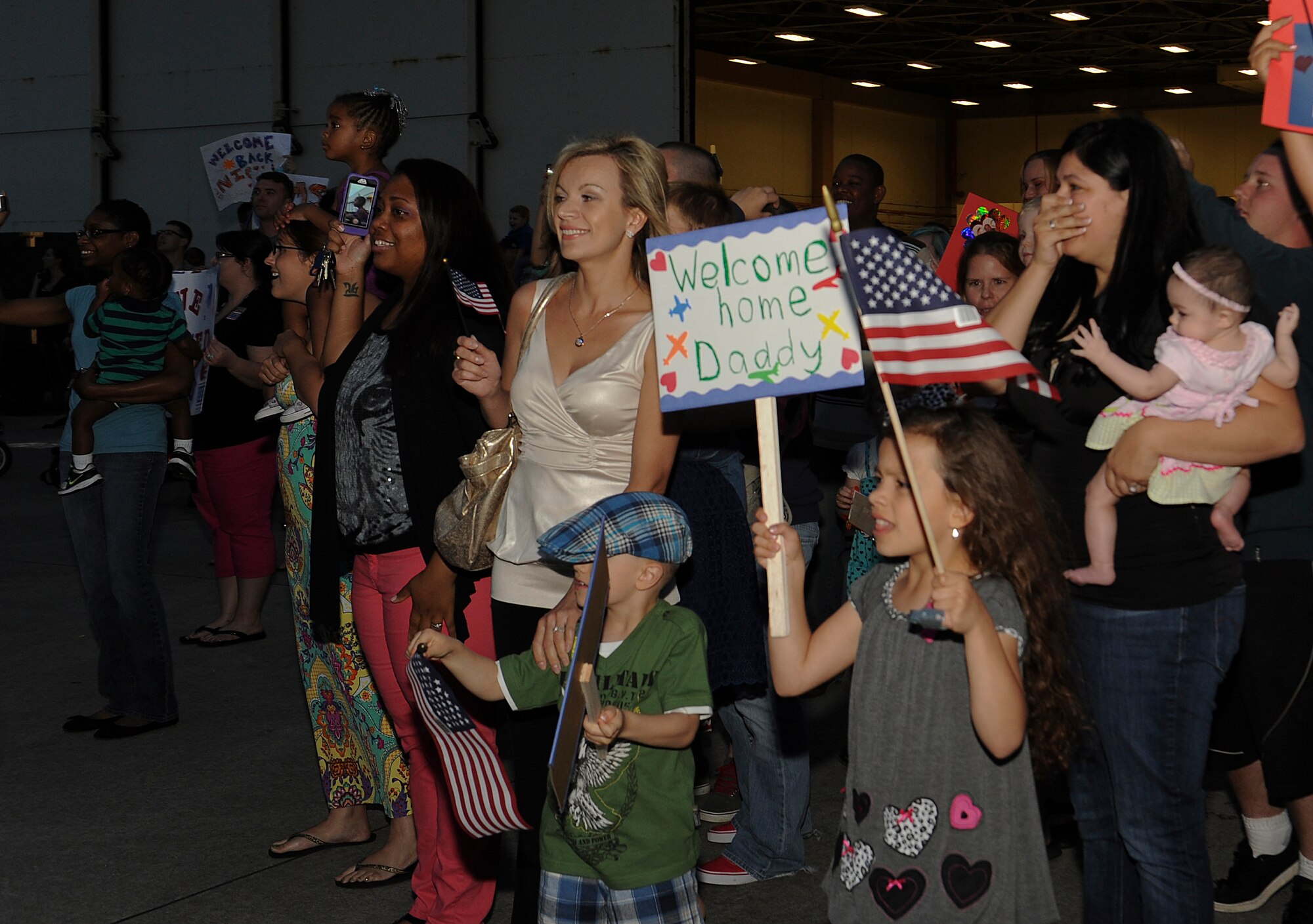 Dozens of family members and friends welcome home loved ones on Kadena Air Base, Japan, May 9, 2013 after the members returned from a deployment. Spouses made various baked goods and banners for the arrival of more than 60 Airmen from the 18th Operations Group who were deployed for eight months. (U.S. Air Force photo by Airman 1st Class Malia Jenkins/Released) 