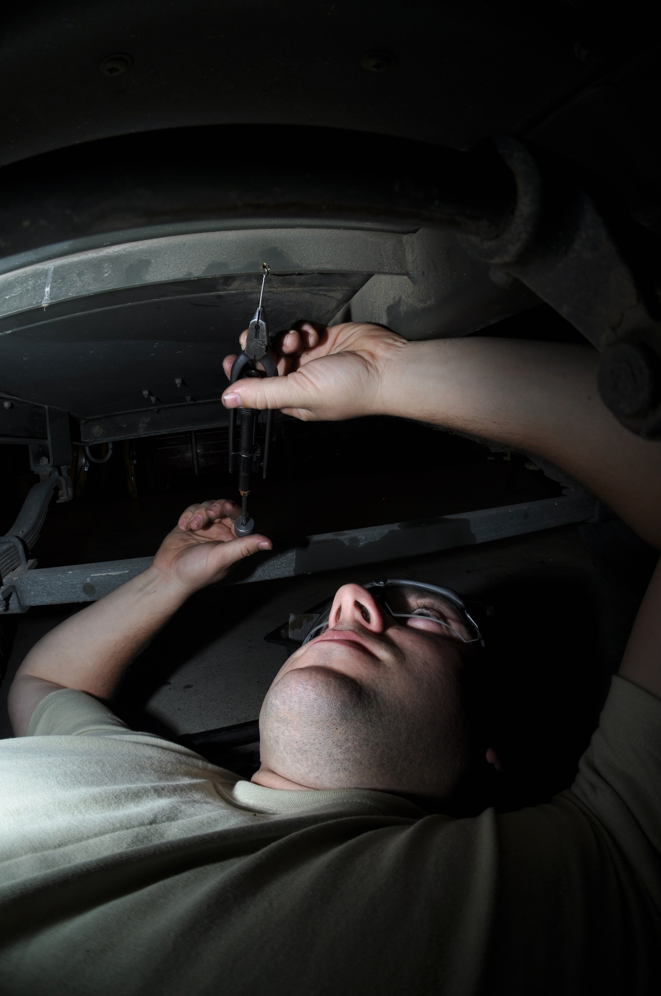 U.S. Air Force Senior Airman Christopher Corley, 380th Expeditionary Maintenance Squadron Aerospace Ground Equipment journeyman, safety wires the underside of a C-10 Air Conditioner May 8, 2013, during a periodic inspection here. AGE provides power, lighting, air conditioning and other essential tools for aircraft maintainers, allowing them to troubleshoot aircraft and maintain mission success. Corley is a Carthage, Miss., native and is deployed from Mountain Home Air Force Base, Ida. (U.S. Air Force photo by Staff Sgt. Timothy Boyer)