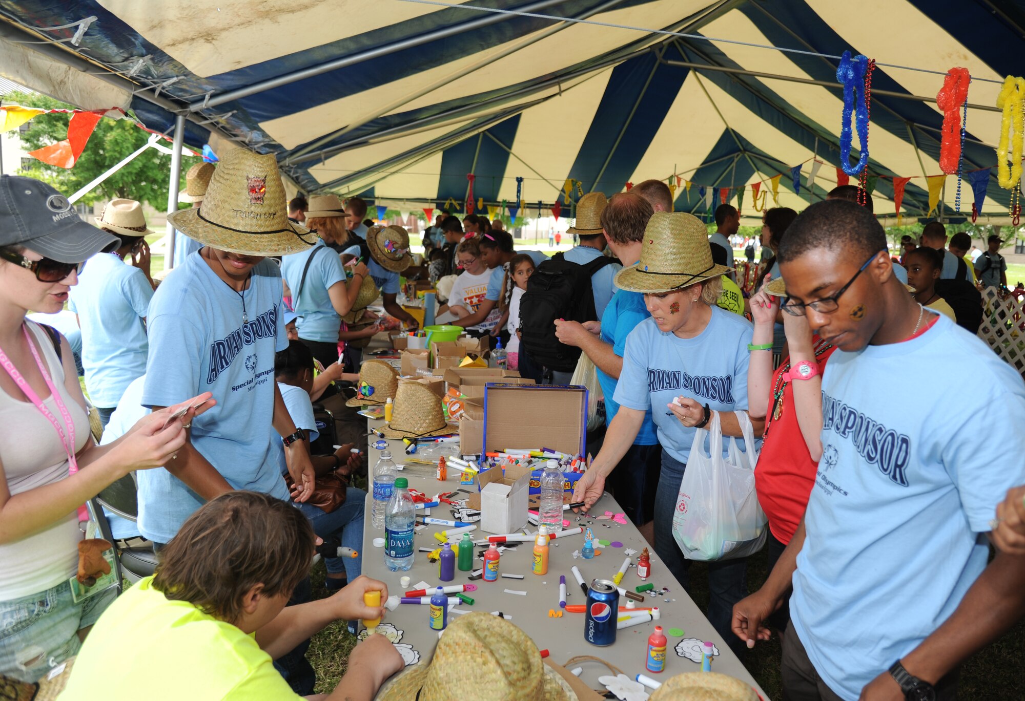 Athletes, sponsors and volunteers gather underneath a tent for arts and crafts at Olympic Village during the Special Olympics Mississippi Summer Games on May 11, 2013, at Keesler Air Force Base, Miss.  More than 900 athletes and 3,000 volunteers worked together to hold competitions throughout the day.  This is the 27th year Keesler has hosted the state Special Olympics.   (U.S. Air Force photo by Kemberly Groue)