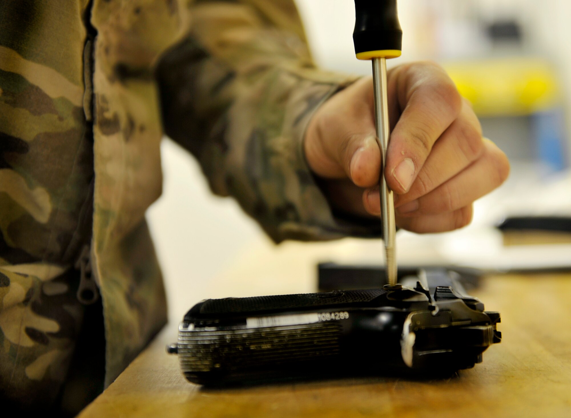 Staff Sgt. Ernesto Boybal, 455th Expeditionary Logistics Readiness Squadron Armory journeyman, disassembles an M9 pistol in order to adjust the magazine release to convert the right-handed weapon to left-handed operation in the armory on Bagram Airfield, Afghanistan, May 10, 2013. With just one piece, the M9 pistol can be converted to operation by the alternate hand for a customer. (U.S. Air Force photo/ Staff Sgt. Stephenie Wade)