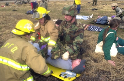 Tech. Sgt. Everett Emerson, an Air National Guard medic from Kulis Air National Guard Base, Alaska, works with firefighters from the North Pole Fire Department to secure a simulated accident victim on a backboard for transportation to the Fairbanks Memorial Hospital May 9. "We've trained for mass casualty exercises, but never this big before," Sergeant Emerson said. The May 9 scenario was part of the Alaska Shield/Northern Edge 2007 exercise which is scheduled from May 7-18. Civilian, military and other government agencies are coming together for the large scale exercise which is designed to test all agencies' preparedness, interaction and response to a variety of incidents ranging from natural disasters to terrorist attacks and other emergencies. 