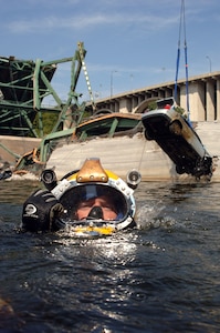 Navy Diver First Class Petty Officer Josuha Harsh of Mobile Diving and Salvage Unit Two (MDSU 2) from Naval Amphibious Base Little Creek, Virginia, surfaces after completing a salvage dive in the Mississippi river as the vehicle he and his team rigged is lifted from the bottom.  Navy divers from MDSU 2 stationed at Naval Amphibious Base Little Creek work in tandem with federal, state, and local government agencies in the search and recovery process.