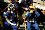 Navy divers from Mobile Dive and Salvage Unit 2 stationed at Naval Amphibious Base Little Creek prepare to enter the water of the I-35 bridge wreckage Aug. 07. When requested by the primary agency and approved by the Secretary of Defense, MDSU 2 may be utilized in support of civil authorities managing disaster recovery efforts. 