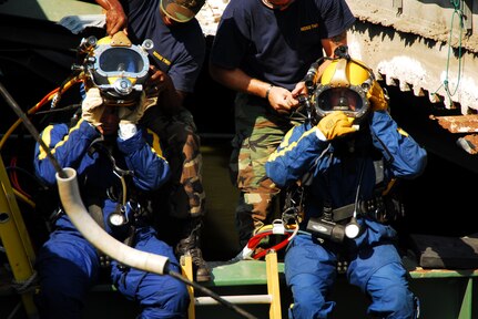 Navy divers from Mobile Dive and Salvage Unit 2 stationed at Naval Amphibious Base Little Creek prepare to enter the water of the I-35 bridge wreckage Aug. 07. When requested by the primary agency and approved by the Secretary of Defense, MDSU 2 may be utilized in support of civil authorities managing disaster recovery efforts. 