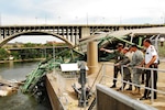 Secretary of the Navy (SECNAV) the Honorable Donald C. Winter, tours the site of the I-35 bridge collapse over the Mississippi river, with Department of Defense, federal, state, and local officials, Aug. 8. Secretary Winter was briefed on the current situation and the progress of the multi-agency search and recovery effort.