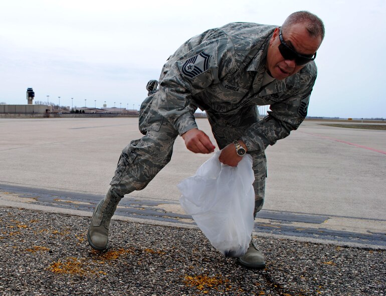 Senior Master Sgt. Victor Correa, 319th Civil Engineer Squadron superintendent of heavy equipment, reaches down to clear paint chips and debris from the flightline on Grand Forks Air Force Base, N.D., on May 10, 2013. Correa was one more than 120 Airmen participating in the base’s FOD (foreign objects or debris) walk that covered an area bigger than 15 square miles. (U.S. Air Force photo/Staff Sgt. Luis Loza Gutierrez)

