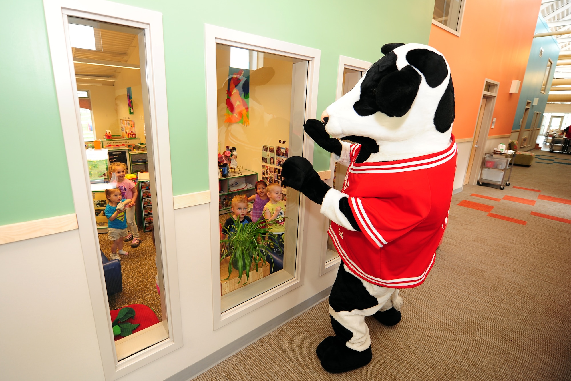 The Chick-fil-A mascot walks down the Child Daycare Center hallway to greet children as part of a Daycare Provider Day donation of 154 prepared lunches to be given to the daycare staff members on May 8 at Offutt Air Force Base, Neb.  The meals included a sandwich, chips, cookie and a choice of sweet or unsweetened tea.  (U.S. Air Force photo by Josh Plueger/Released)