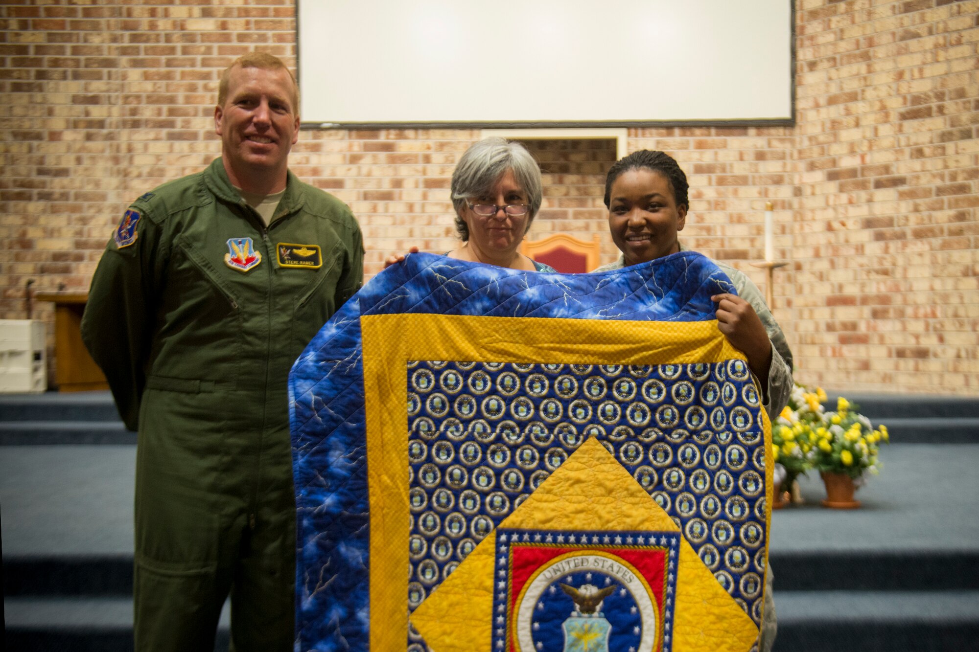 Louise Smith, Quilts of Valor Foundation member, presents a quilt to U.S. Air Force Senior Airman Shatavia Wallace, 824th Base Defense Squadron, May 8, 2013, at Moody Air Force Base, Ga. Quilts of Valor is an organization comprised of volunteers who make quilts for service members and veterans who have suffered or received injuries from combat. (U.S. Air Force photo by Staff Sgt. Jamal D. Sutter/Released)   