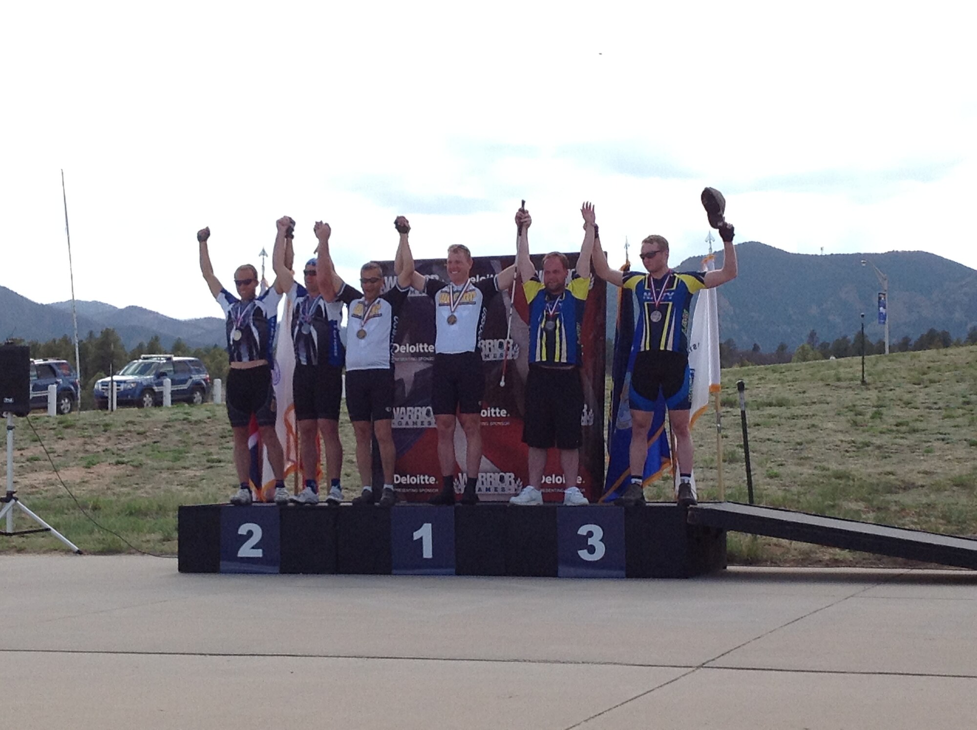 Competitors of the mixed tandem cycling event raise their arms in celebration May 12 at the 2013 Warrior Games medal ceremony near Falcon Stadium. Winning the gold was the Special Operations Command team, with Air Force coming in second place, and Navy placing third.
